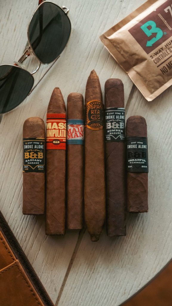 Cigars, sunglasses, and a humidor pack arranged on a surface.